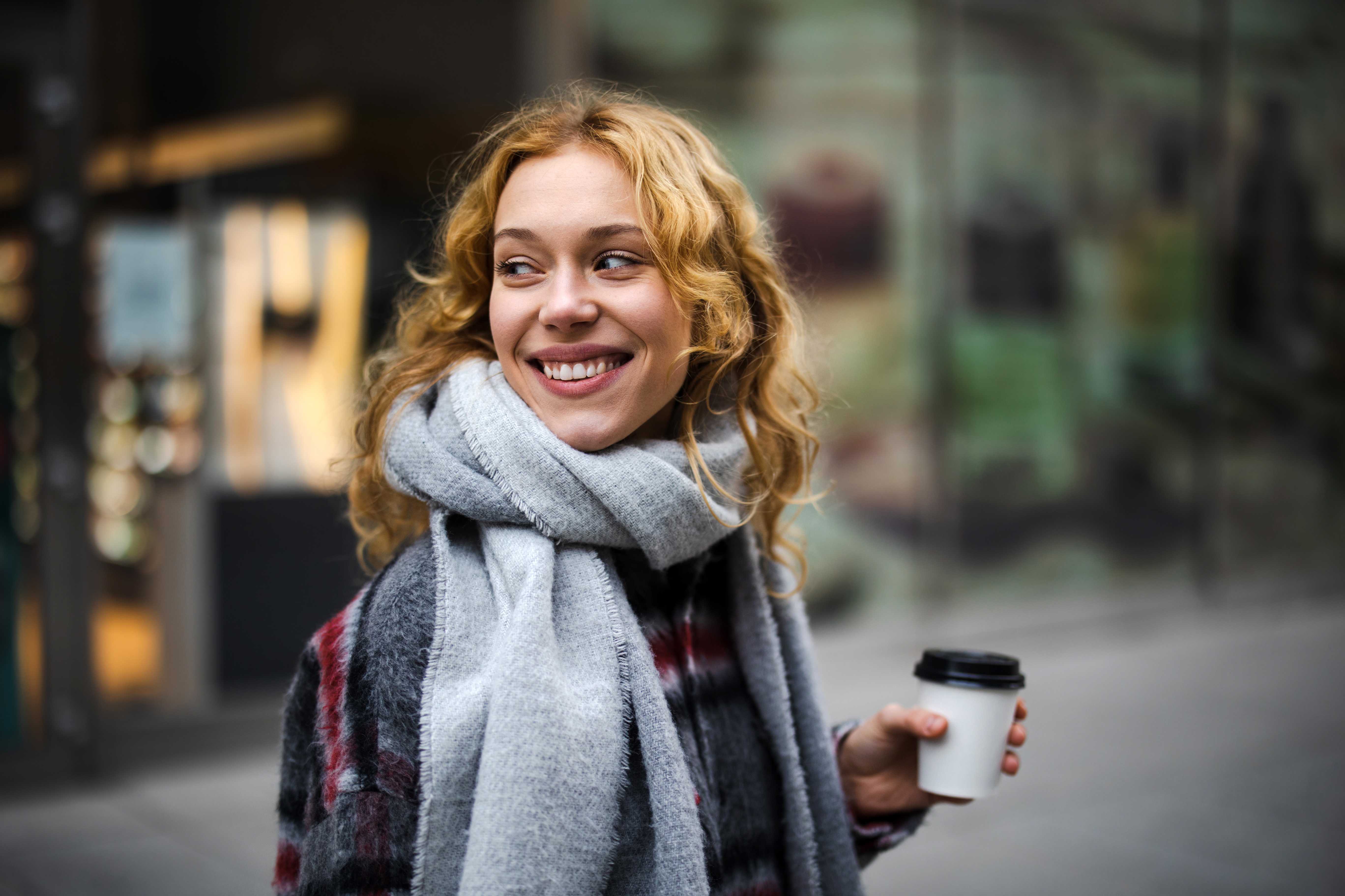 Personne tenant une tasse de café et souriant